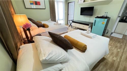 a hotel room with two beds and a television at Daddy Dream Hotel and Residence in Ranong