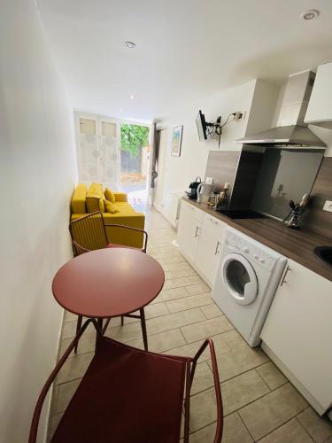 une cuisine avec un lave-linge, une table et des chaises dans l'établissement Studio collioure mouret, à Collioure