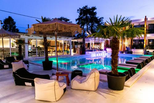a swimming pool with chairs and palm trees next to a building at Avaton Luxury Resort and Spa Access the Enigma - Adults Only & Kids 14 Plus- in Asprovalta