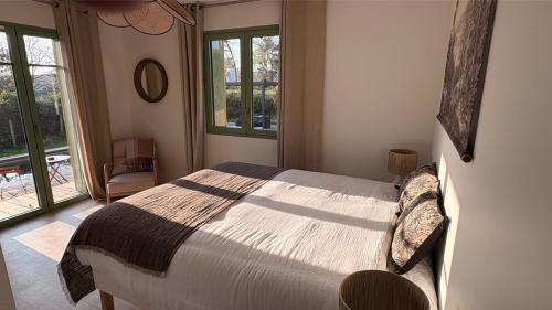 une chambre avec un lit dans une pièce avec des fenêtres dans l'établissement Villa rénovée sur Bassin d'Arcachon, à La Teste-de-Buch