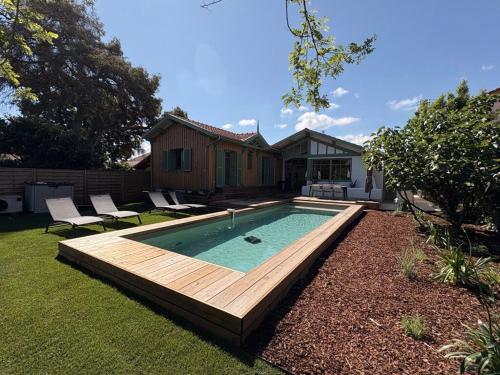 une piscine avec une terrasse en bois et une maison dans l'établissement Villa rénovée sur Bassin d'Arcachon, à La Teste-de-Buch