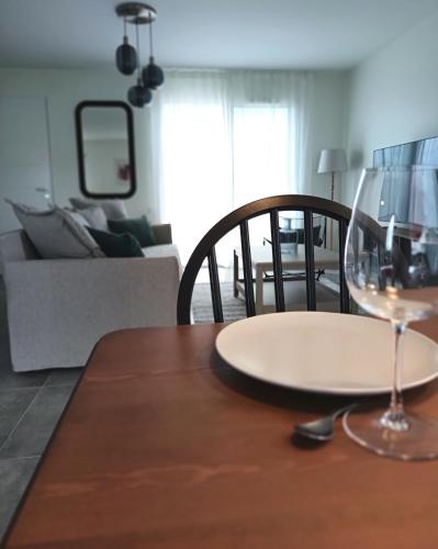 a table with a plate and a wine glass on it at L'Orge - Maison Design, 3 chambres, jardin et garage privatif in Vic-le-Comte