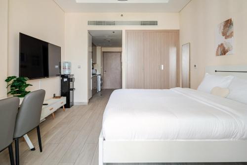 a white bedroom with a large white bed and a desk at Cosy studio Free Parking Free unlimited drinkable water Near Downtown in Dubai