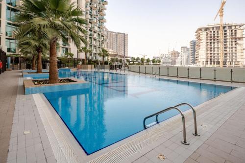 a large swimming pool with a palm tree in a city at Cosy studio Free Parking Free unlimited drinkable water Near Downtown in Dubai