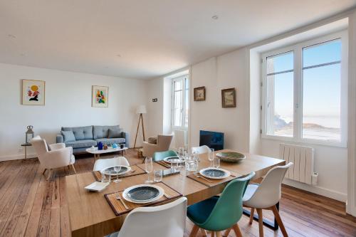 une salle à manger et un salon avec une table et des chaises dans l'établissement full sea view with direct beach access, à Dinard