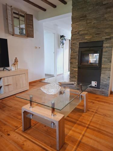 a living room with a glass table and a fireplace at Le Gai Pinson in Beausaint