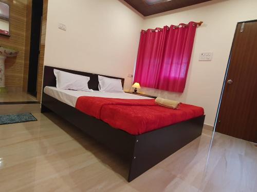 a bed in a room with a red window at Serina House Malvan in Malvan