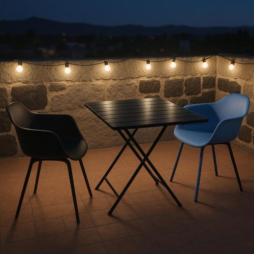 deux chaises assises à côté d'une table noire avec des lumières dans l'établissement Gite de la tour, proche Nîmes ,Avignon, à Montfrin