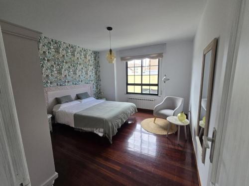 a bedroom with a bed and a window and a chair at Winahost Salvora en Primera Línea de Mar in Ribeira
