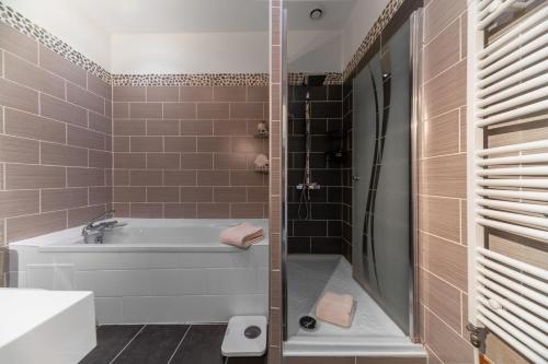 a bathroom with a tub and a shower with brown tiles at Maison Petillat - Calme en plein centre - 2 chambres 80m2, Wifi in Vichy
