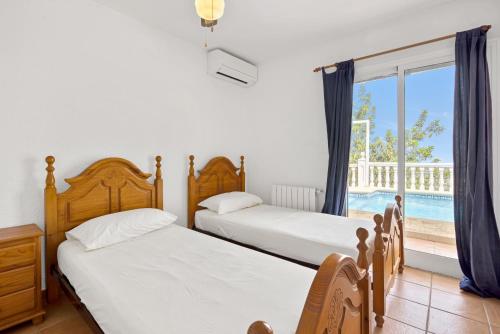 Casa Amanda في Muntanya la Sella: سريرين في غرفة نوم مطلة على مسبح