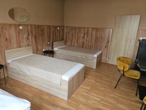 two beds in a room with wooden walls and wooden floors at Hotel Taurus in Ostrava