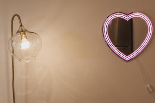 a heart shaped mirror on a wall next to a lamp at Birch Street Solo Haven in Lower Hutt
