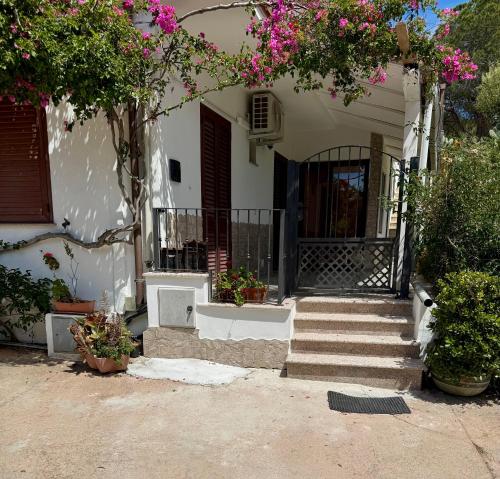 a white house with a staircase and flowers at So close to the sea in Santa Maria Navarrese