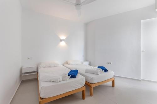 two beds in a room with white walls at Hastinapura, acceso directo al mar in Es Castell