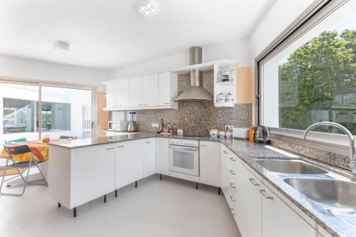 a kitchen with white cabinets and a large window at Hastinapura, acceso directo al mar in Es Castell