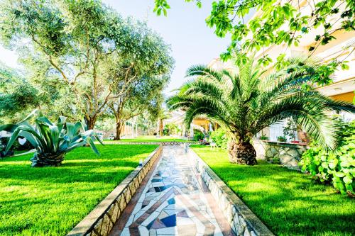 a garden with a palm tree and a walkway at Resort Trcol in Novalja