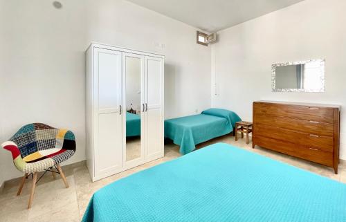 a bedroom with two beds and a cabinet and a chair at CASA ELAIO - immersa negli ulivi con vista sul mare Ionio in Marina San Gregorio