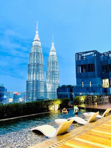 a group of chairs in a pool in front of tall buildings at My Residence Villa Star Klcc in Kuala Lumpur