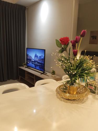 a table with a vase of flowers and a television at My Residence Villa Star Klcc in Kuala Lumpur