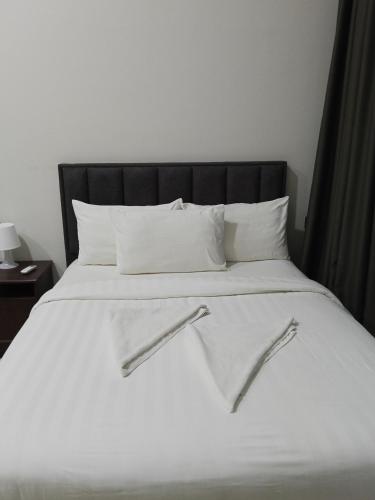 a white bed with a black headboard and white pillows at My Residence Villa Star Klcc in Kuala Lumpur
