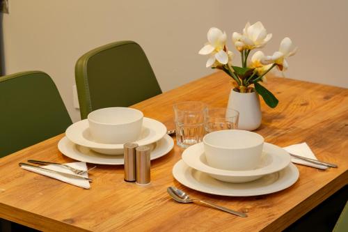 a wooden table with white dishes and a vase of flowers at The Han YK Hotel in Avcılar
