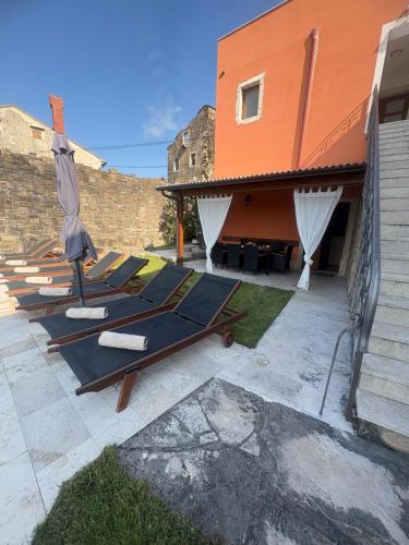 a patio with lounge chairs and an orange building at Villa Letizia in Oprtalj