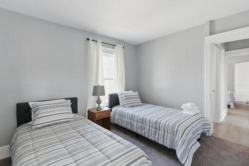 two beds in a bedroom with white walls and windows at Modern 6BR Near Syracuse U, Destiny & Zoo Sleeps 18 in Syracuse