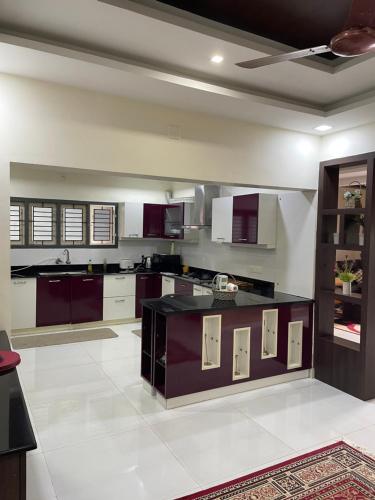 a large kitchen with purple cabinets and white appliances at Castle villa in Ernakulam