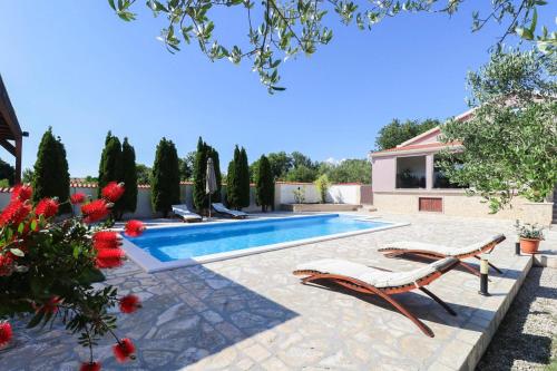 a swimming pool with two lounge chairs and flowers at Villa Marija ZadarVillas in Poličnik