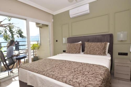 a bedroom with a bed and a woman sitting at a desk at IDEE SUİTES Fethiye in Fethiye