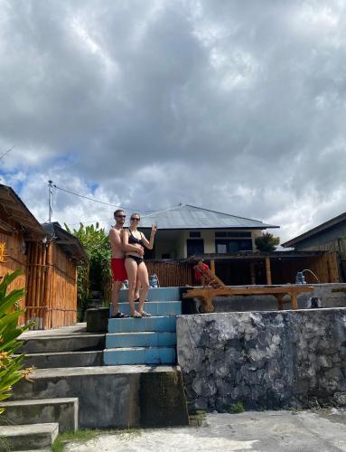 two people sitting on the stairs of a house at Volcano Living in Kintamani