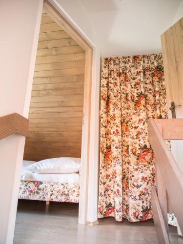 a bedroom with a bed with a floral curtain at Mała Osada domki z jacuzzi przy gondoli in Szczyrk