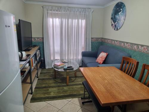 a living room with a blue couch and a table at Heart of Modbury in Modbury