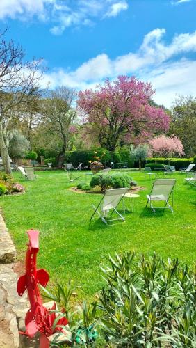 a group of lawn chairs in a park with flowering trees at Logis Hôtel Château De Palaja in Carcassonne