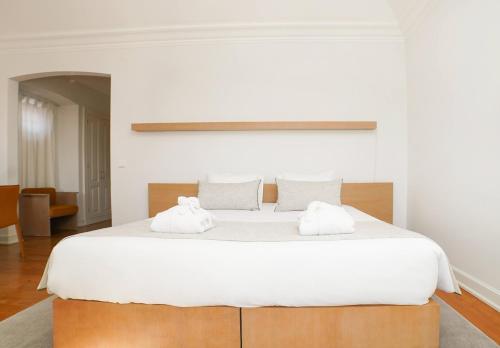 a bedroom with a large white bed with two towels at Solar das Bouças by Quantique in Amares
