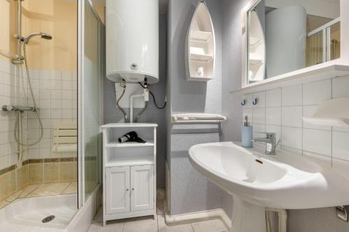 une salle de bain blanche avec un lavabo et une douche dans l'établissement Appartement RDC pour 4 à 800m de la mer, à Pornic
