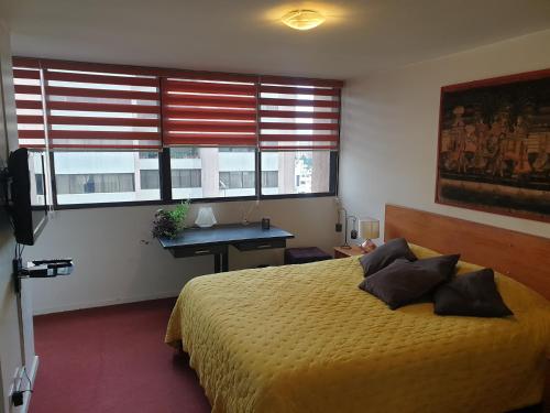 a bedroom with a bed and a desk and a window at French Suite Cordero in Quito