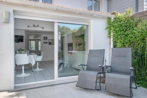 une porte coulissante en verre avec deux chaises sur la terrasse. dans l'établissement Vue mer, plage à 50m, Maison pour 4, à La Plaine-sur-Mer