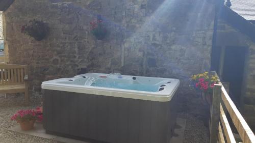 a hot tub in front of a stone wall at A Cozy Bothy Retreat with Hot Tub in Keilour