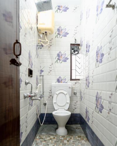 a bathroom with a toilet with purple flowers on the wall at Mahes Villa - Svenks Hotels in Chennai