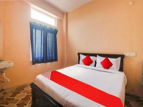 Un dormitorio con una cama con almohadas rojas y una ventana. en Hotel O R.J.international, en Pedda Ambarpet