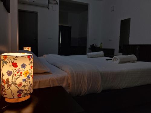 a bedroom with a bed and a lamp with a flower pattern at Auro Maison in Puducherry