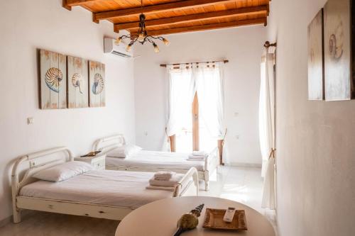 a room with two beds and a table in it at The Beach House Μουτσούνα Νάξος in Moutsouna Naxos