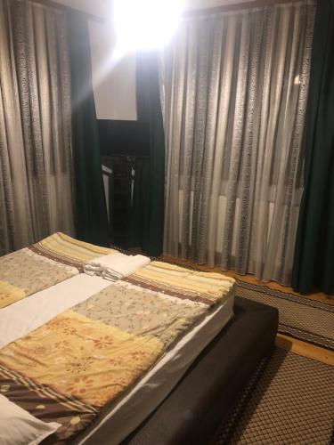 a bed sitting in front of a window with curtains at Bayrakova Guest House in Dobrinishte