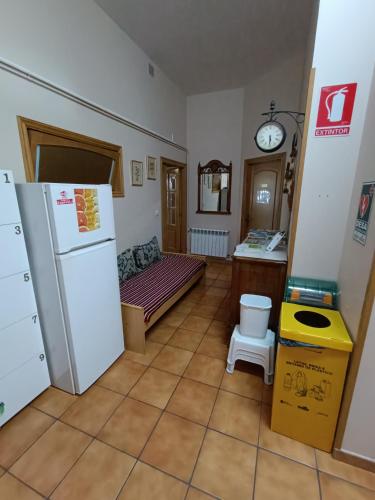 a kitchen with a refrigerator and a bench in a room at Albergue Ultreia Sigueiro in Sigüeiro