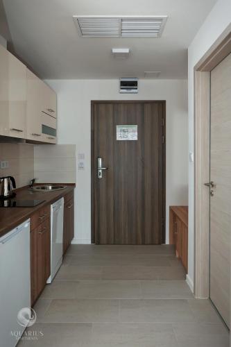 a kitchen with a wooden door in a room at Aquarius Apartments in Miskolctapolca
