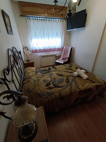 a bedroom with a bed and a chair and a window at Albergue Ultreia Sigueiro in Sigüeiro