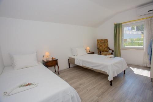 a bedroom with two beds and a chair and a window at Apartments - House Monarch - beach, center & shared pool access in Sutivan