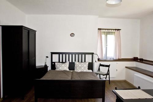 a bedroom with a bed with a chair and a window at Penzion Albeř in Nová Bystřice